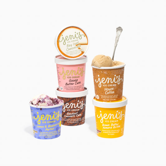 Five pints of Jeni's Ice Cream in various flavors on a white background