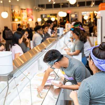 Employees at a 168一分钟极速赛车官网's scoop shop scooping ice cream for customers.