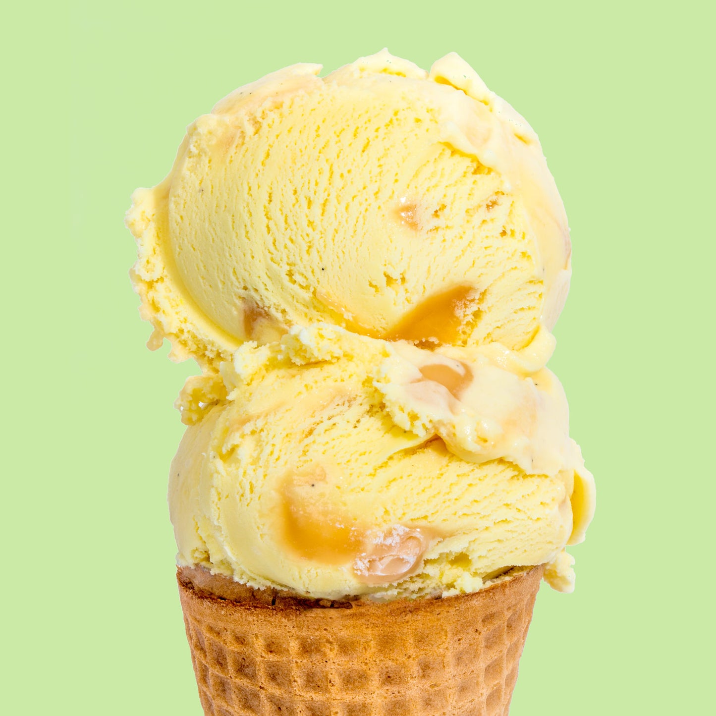 A scoop of golden nectar ice cream on a waffle cone