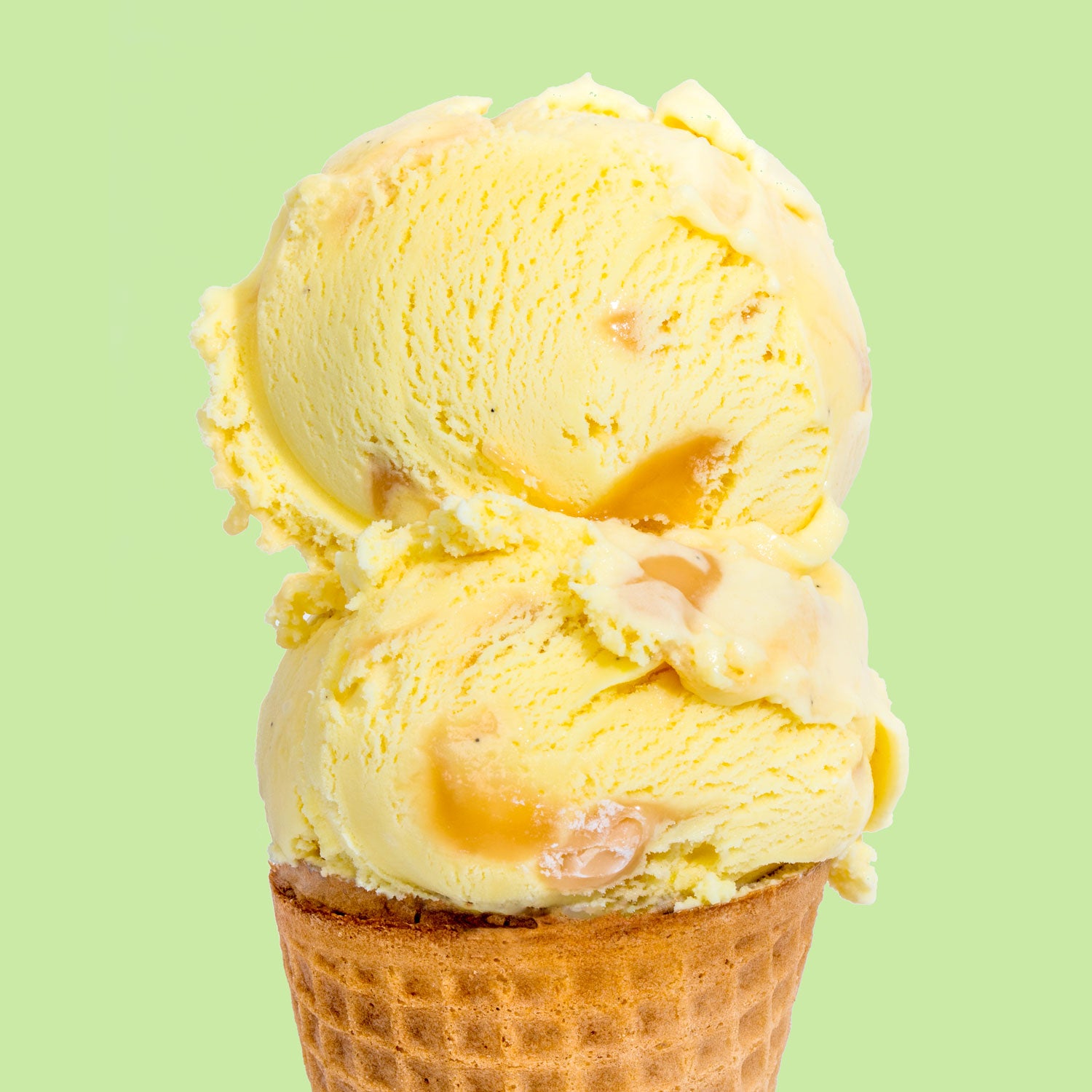 A scoop of golden nectar ice cream on a waffle cone